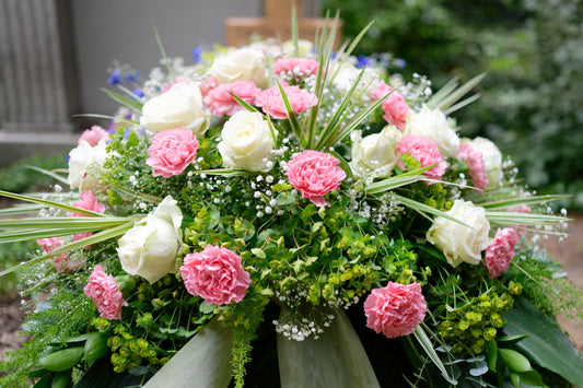 Elegant white peonies and greenery arranged in a marbled gray vase with ribbon detail
