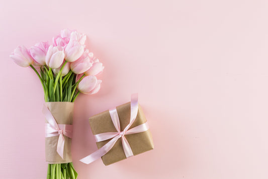 Bouquet of white roses and flowers with green leaves wrapped in beige paper with a satin ribbon.