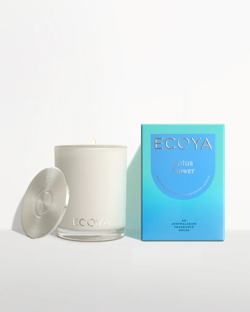 A white ECOYA candle with a silver lid next to its blue packaging box.