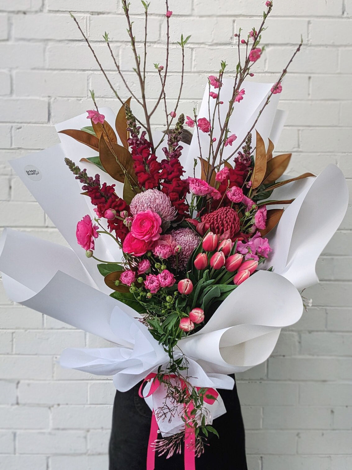 Lovely bouquet featuring pink flowers, beautifully wrapped with a white ribbon.