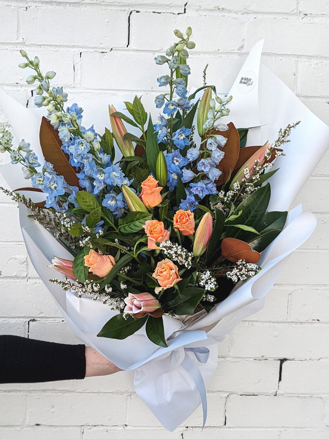 Colorful assortment of flowers elegantly displayed in a white paper bag, highlighting their natural beauty.