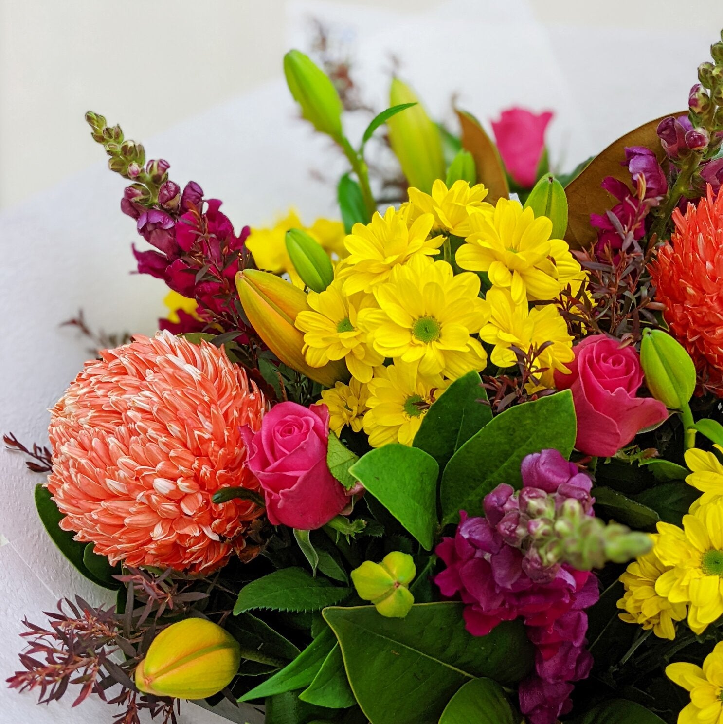 Vibrant bouquet with yellow chrysanthemums, pink roses, and orange blooms.