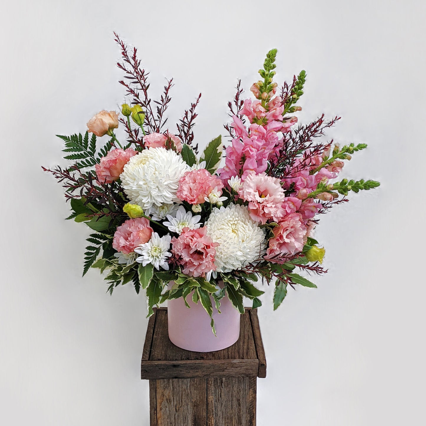Elegant flower arrangement featuring pink and white blooms, artfully presented in a charming wooden box.