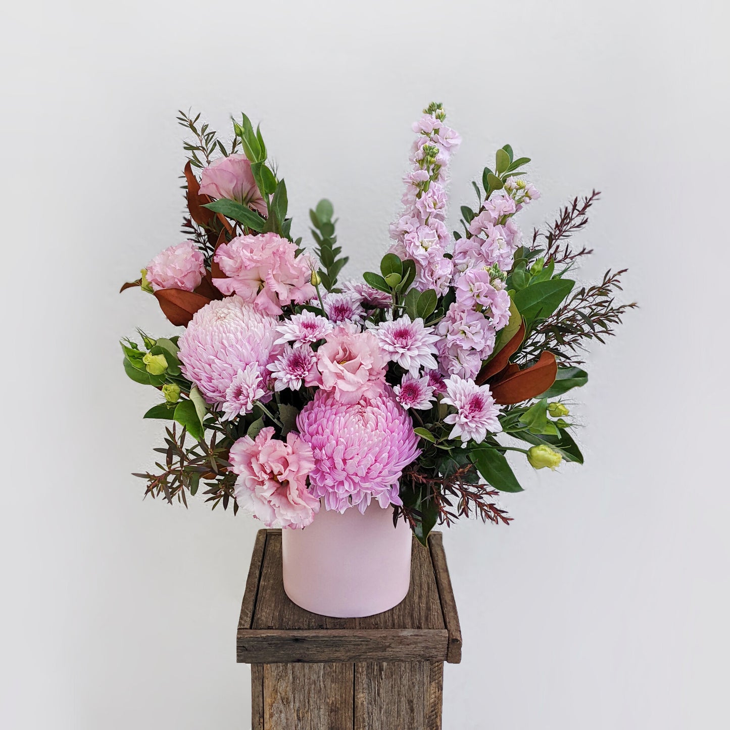 Elegant flower arrangement featuring pink and white blooms, artfully presented in a charming wooden box.
