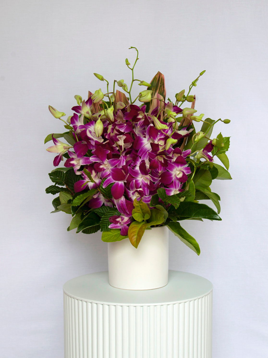 A white vase adorned with red roses and green foliage, presenting a beautiful and classic floral composition