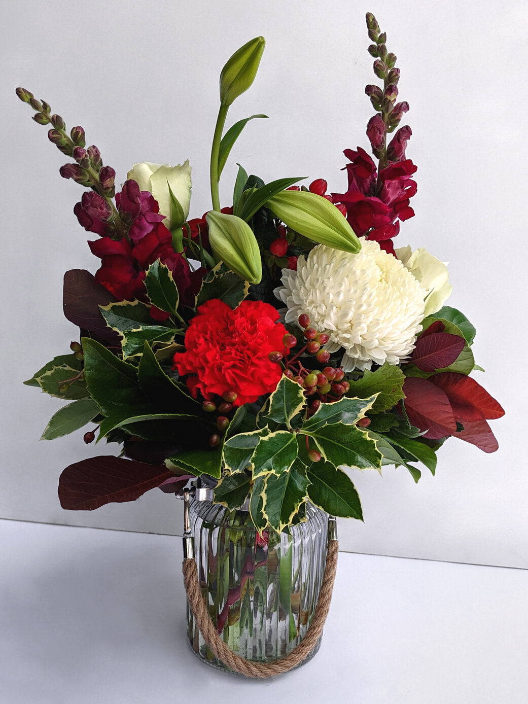 A vibrant bouquet of red, white, and green flowers arranged in a glass vase.